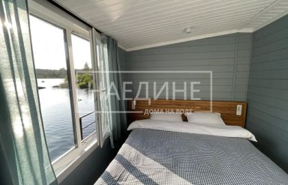 Удобная двуспальная кровать в хаусботе с постельным бельем и видом на воду
