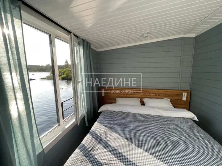 Удобная двуспальная кровать в хаусботе с постельным бельем и видом на воду